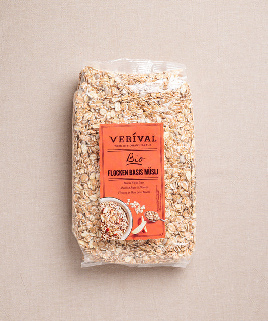 Eine Packung Flocken Basis Müsli von Verival Bio mit orangefarbenem Etikett, auf dem Haferflocken und eine Schüssel Müsli abgebildet sind. Sie ist versiegelt und steht vor einem neutralen Hintergrund.