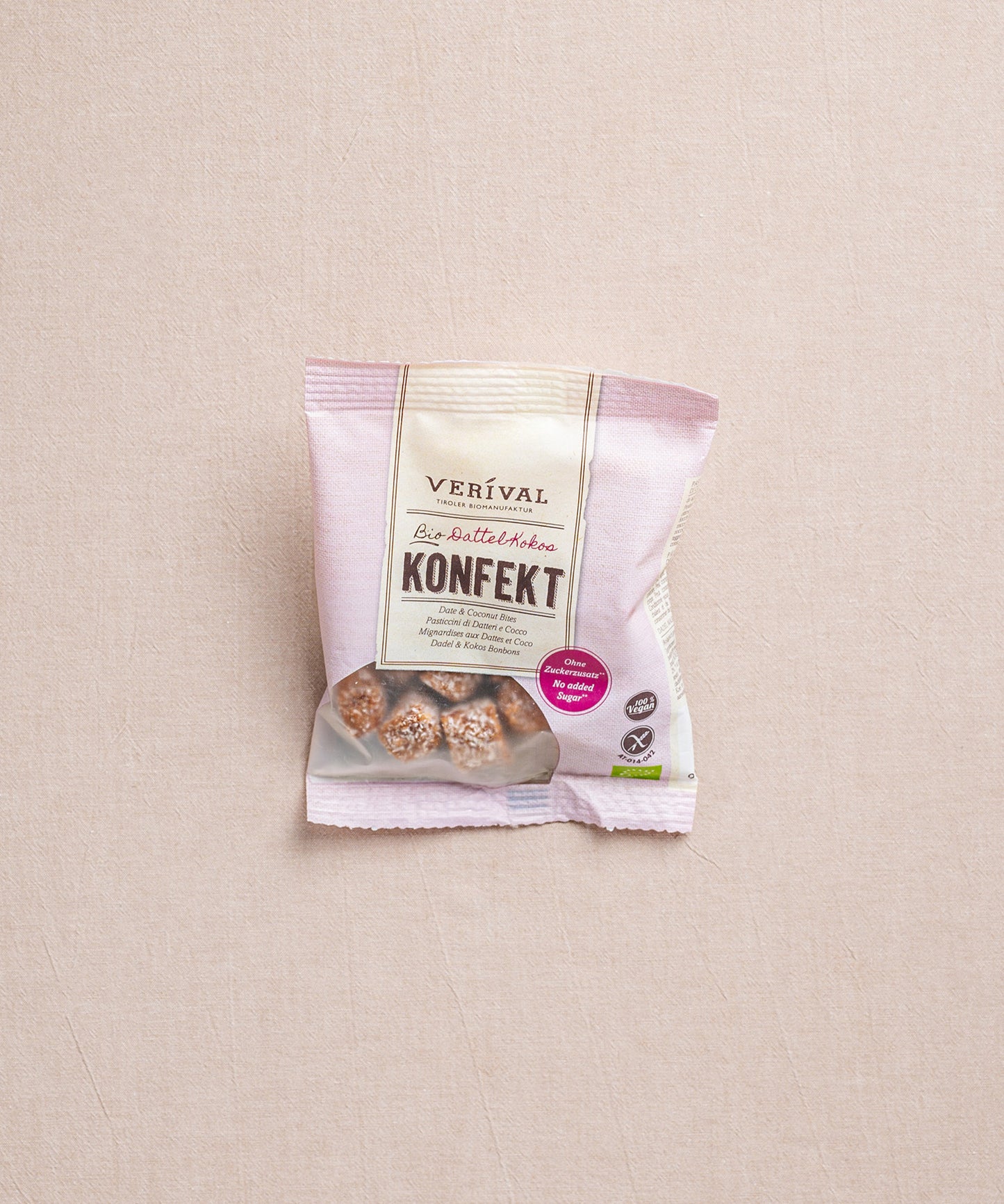 Eine Packung Dattel-Kokos Konfekt von Verival Bio, mit 100% Bio-Datteln, liegt auf einer beigen Oberfläche.