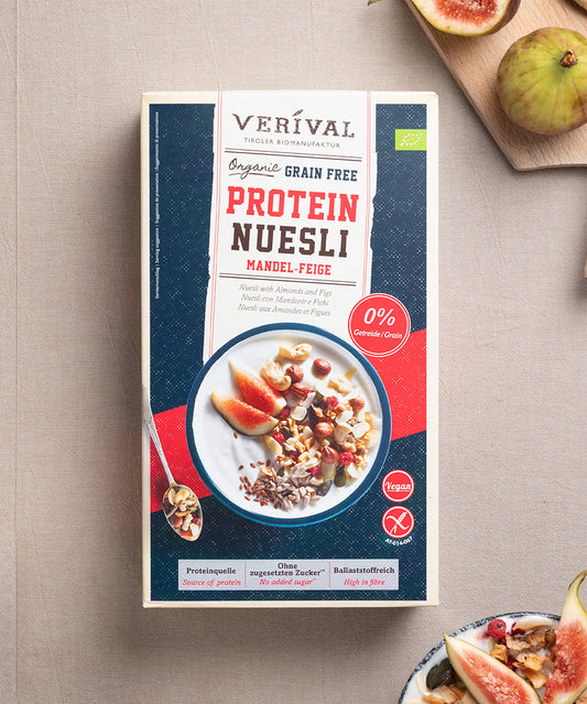 Eine Packung Grain Free Protein Nüsli Mandel-Feige von Verival Bio steht zusammen mit einer Schüssel dieses glutenfreien Low-Carb-Müslis auf einem Tisch mit gemütlicher Frühstücksatmosphäre.