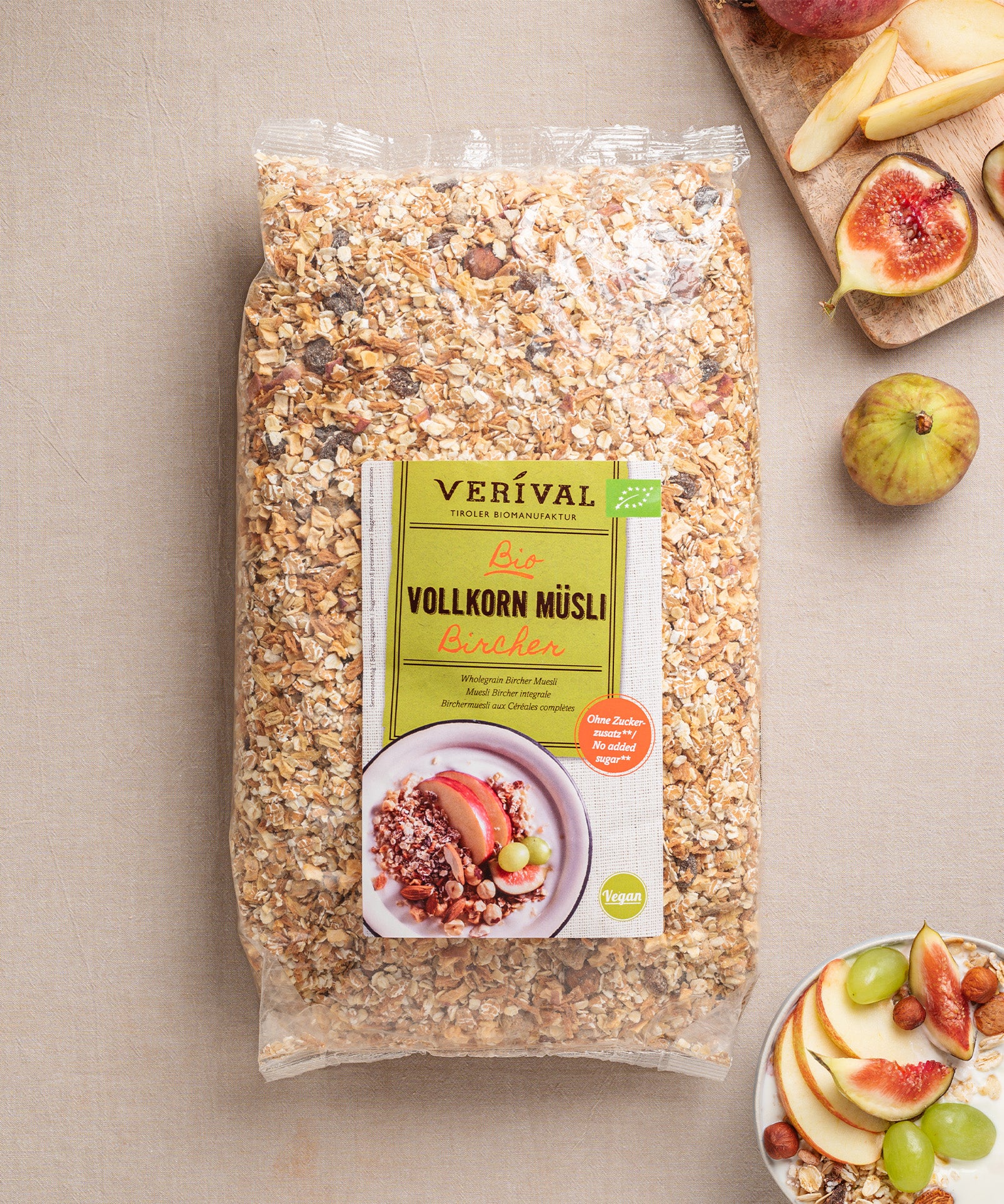 Das Bircher Vollkorn Müsli von Verival Bio zeigt auf dem Etikett eine Müslischale mit Früchten, umgeben von Apfelscheiben, Feigen und Nüssen. Der vegane Genuss ist reich an Ballaststoffen und sorgt für einen gesunden Start in den Tag.